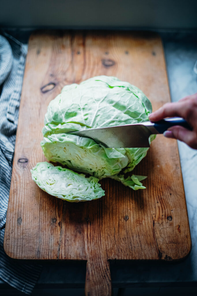 Slicing green cabbage thinly to make a delicious coleslaw salad.